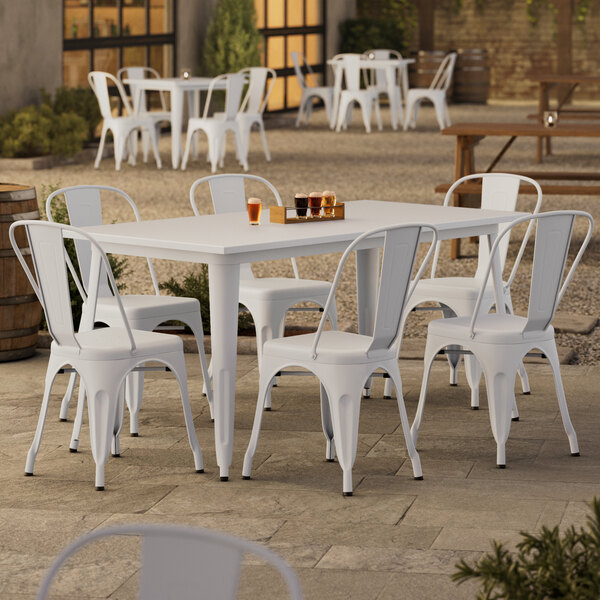 A Lancaster Table & Seating white table with chairs on an outdoor patio.