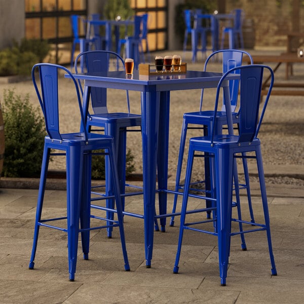 A Lancaster Table & Seating blue metal bar table with four blue chairs.