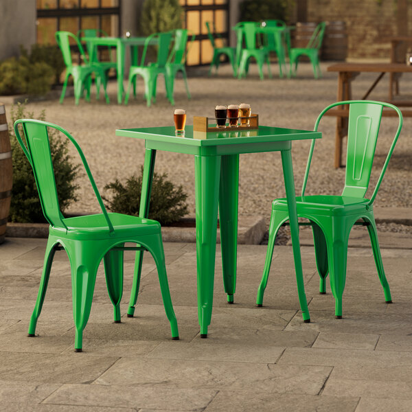 A jade green Lancaster Table & Seating outdoor table with chairs on a stone patio.