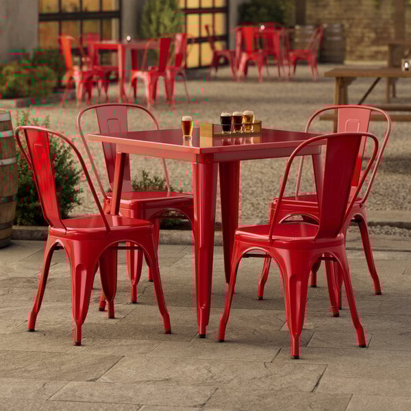 A red metal Lancaster Table & Seating outdoor table with chairs.