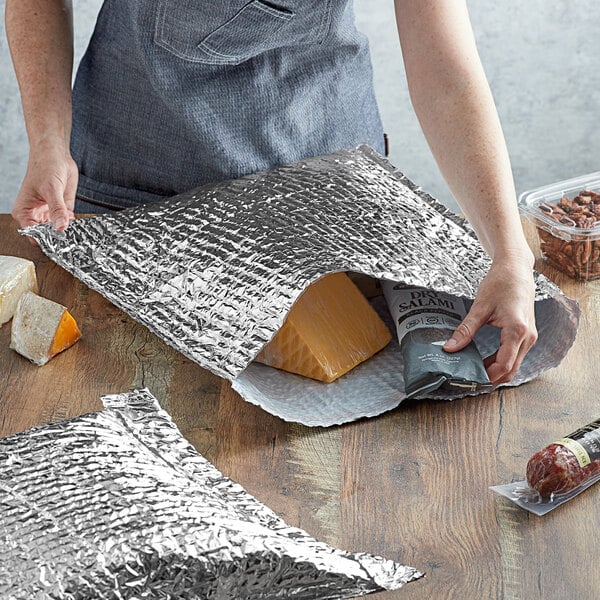 A woman using a Lavex insulated foil bag to open a bag of salami.