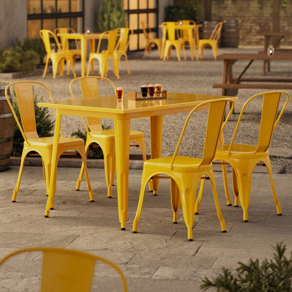 A Lancaster Table & Seating citrine yellow table and chairs on a patio.