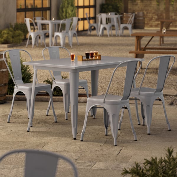 A Lancaster Table & Seating outdoor table and chairs with metal legs on a patio.