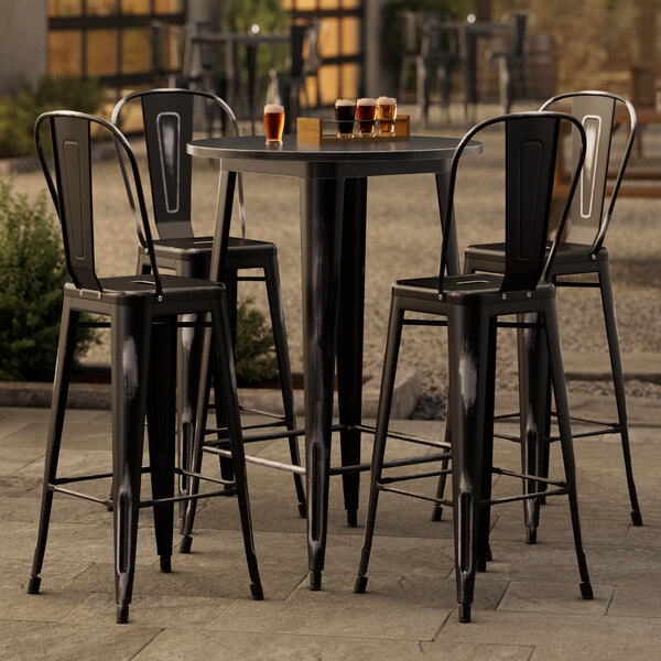A Lancaster Table & Seating black bar height outdoor table with 4 black chairs.