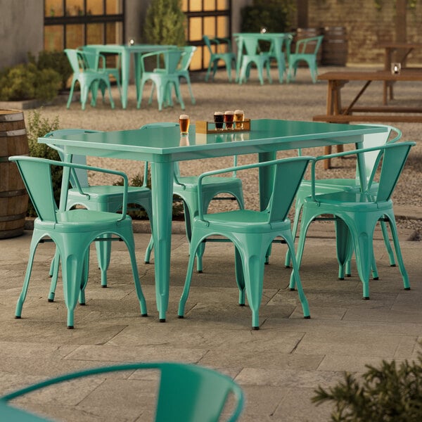 A Lancaster Table & Seating aquamarine table with green chairs on a patio.