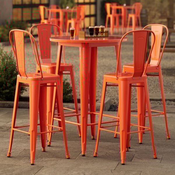 A Lancaster Table & Seating round amber orange outdoor table with 4 cafe barstools.