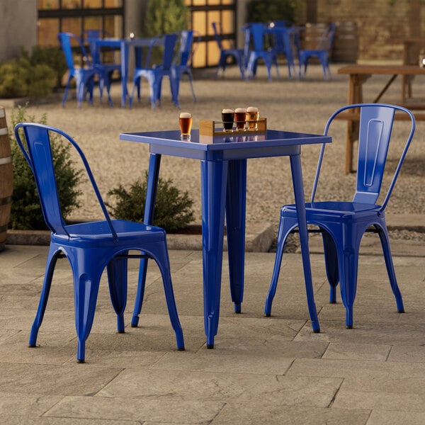 A blue table with two blue chairs on an outdoor patio.