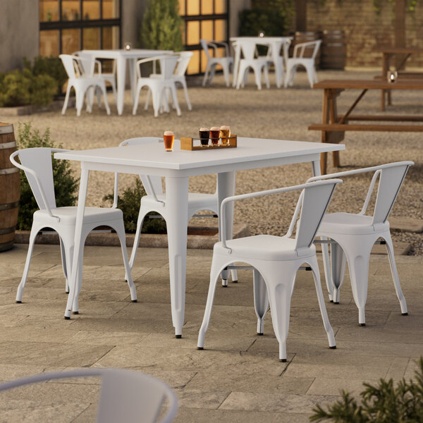 A Lancaster Table & Seating white table with 4 arm chairs on a patio.