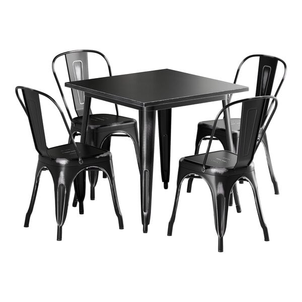 A Lancaster Table & Seating distressed onyx black metal table with four chairs.