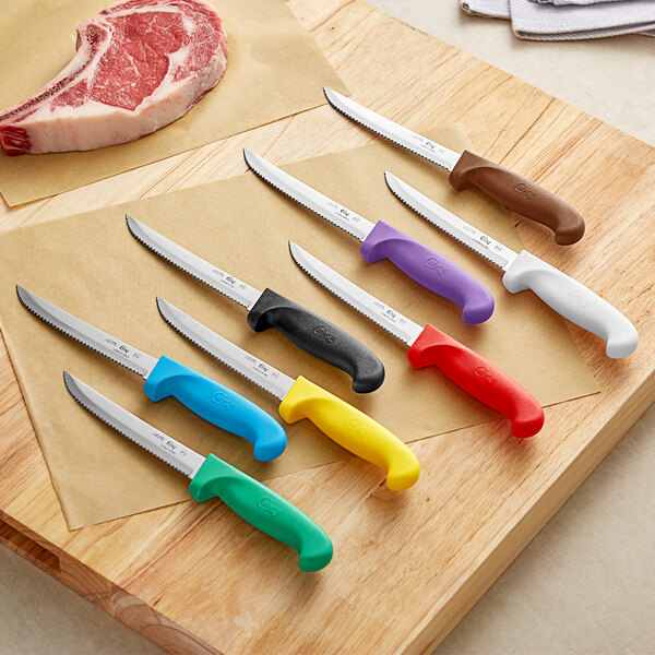 A group of Choice utility knives with colorful handles on a cutting board.