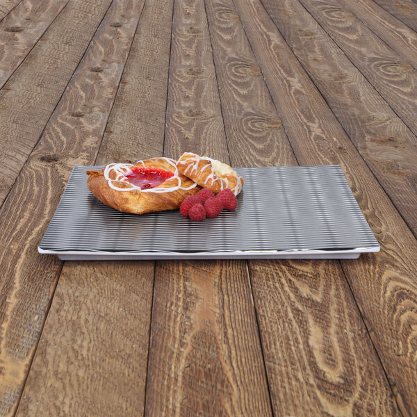 A black Elite Global Solutions melamine platter with a pastry and a raspberry on it.
