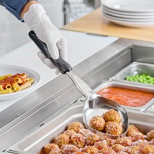 A person wearing gloves uses a Vollrath black oval portion spoon to serve meatballs with sauce.