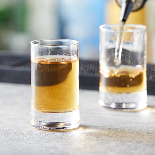 A Nude Rocks shot glass filled with liquid being poured into another glass.