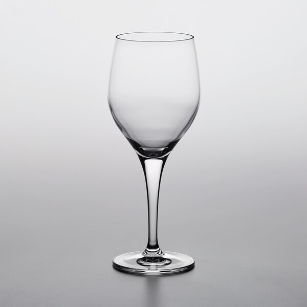 A close-up of an empty Nude Primeur wine goblet on a white background.
