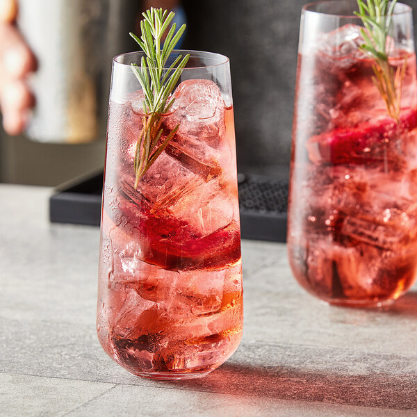 Two Nude Mirage long drink glasses filled with pink drinks and rosemary sprigs.