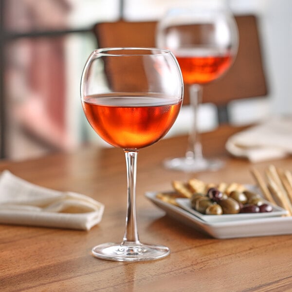 Two Nude Reserva wine glasses filled with red wine on a table.