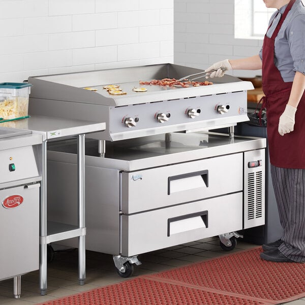 A person cooking food on a large countertop griddle.