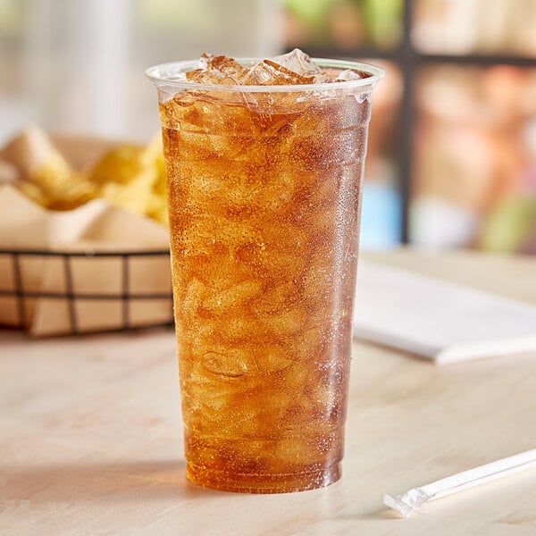 A 24 oz EcoChoice PLA compostable plastic cold cup filled with ice tea on a table.