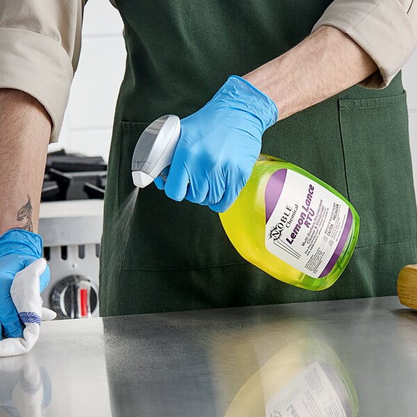 A person in gloves using Noble Chemical Lemon Lance to clean a counter.