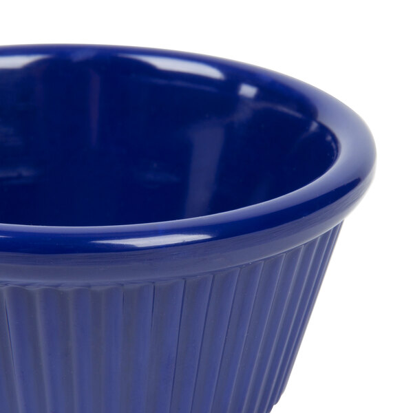 A close up of a navy blue fluted ramekin with a rim.
