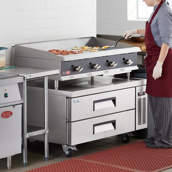 A woman cooking food on a Cooking Performance Group countertop griddle.