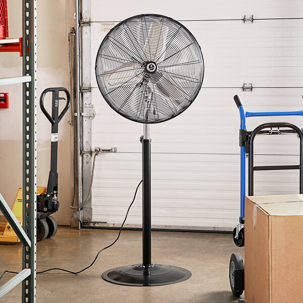 A black TPI industrial pedestal fan on a stand.