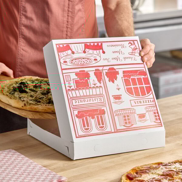A white 12-inch square pizza box with red printed graphics and customizable design, shown being used to package a pizza.