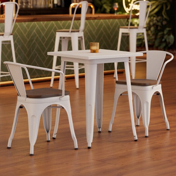 A Lancaster Table & Seating white table and 2 chairs with walnut seats in a restaurant dining area.