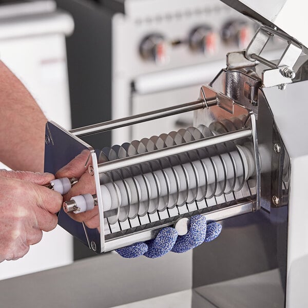 A person's hands using an Avantco meat tenderizer machine to cut meat.