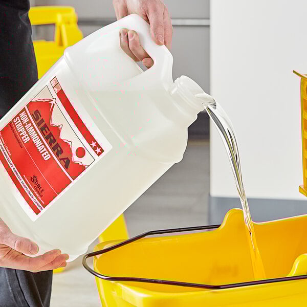 A person pouring Sierra by Noble Chemical non-ammoniated concentrated stripping floor finish into a bucket.