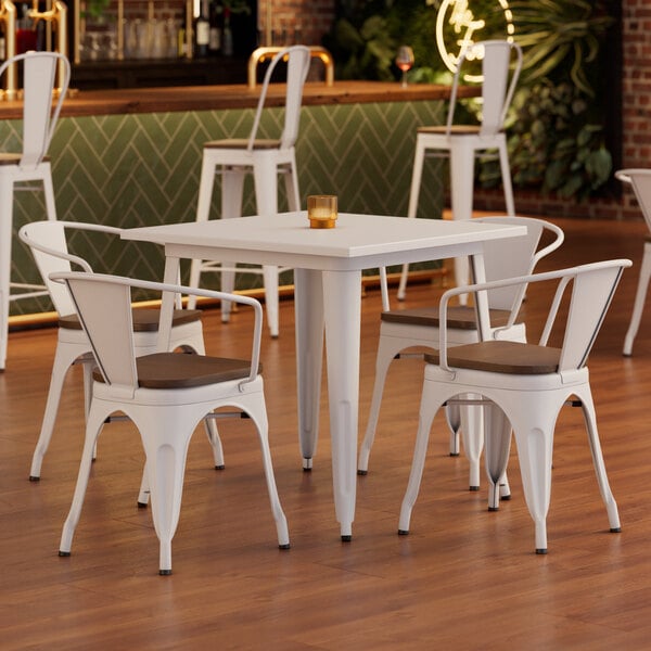 A Lancaster Table & Seating white table and chairs with walnut seats in a restaurant dining area.