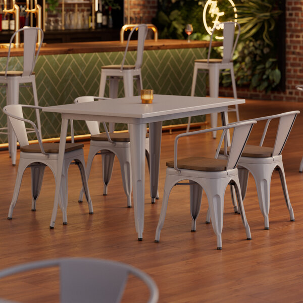 A Lancaster Table and Seating table with white legs and 4 white chairs with wooden seats.
