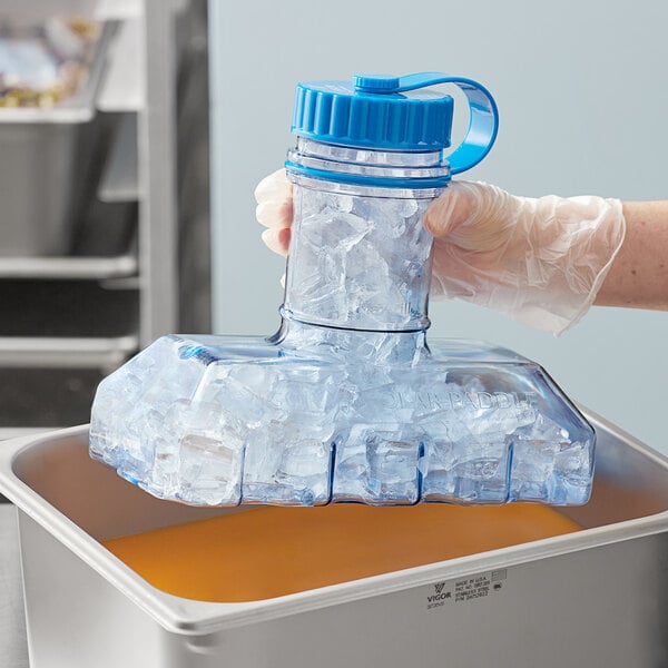 A gloved hand holding a Vigor Polar Paddle with ice.