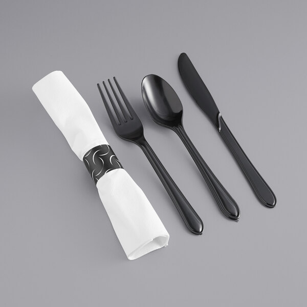 A white napkin with black heavy weight cutlery, including a fork and spoon.