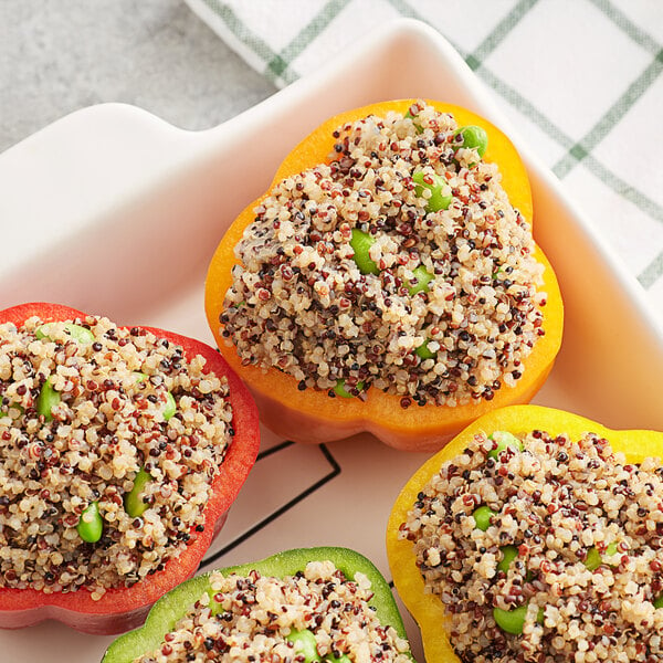 A white dish of stuffed peppers with Furmano's tri-color quinoa and peas.