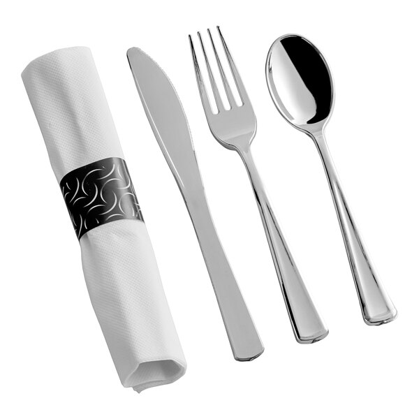 A pre-rolled white napkin with a metallic silver napkin ring, accompanied by a set of extra heavy weight metallic silver cutlery including a knife, fork, and spoon.