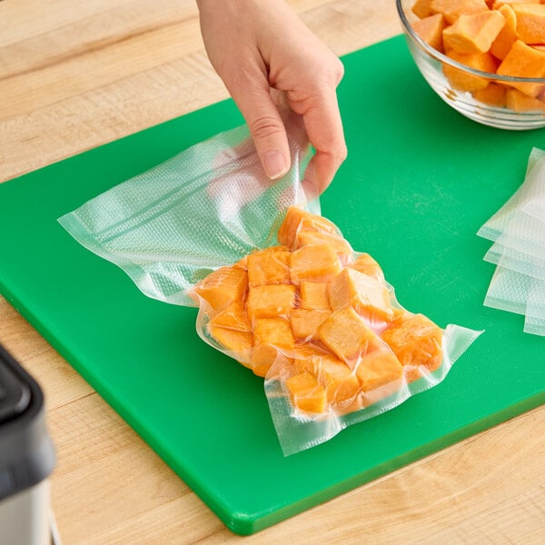 A vacuum-sealed bag containing cubed orange food items, shown on a green cutting board.