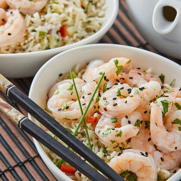 An Asian rice bowl prepared with medium sized shrimp, peppers, and sesame seeds
