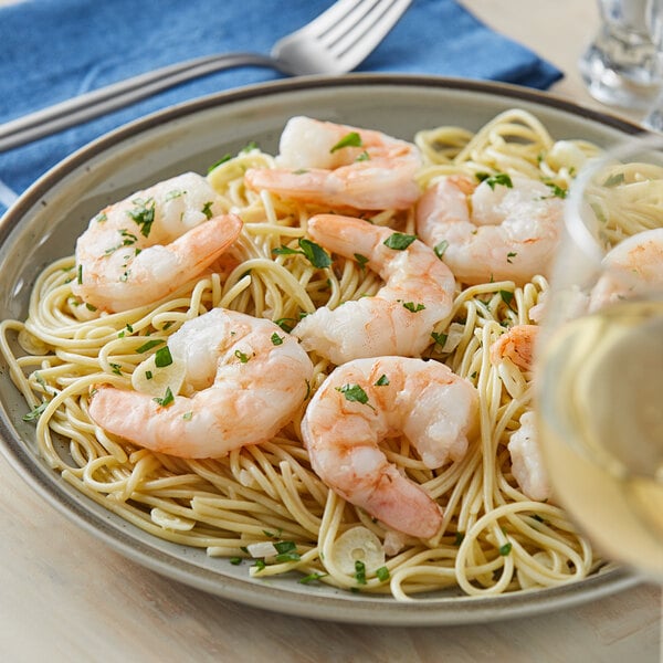 A plate of shrimp scampi noodles topped with colossal sized shrimp