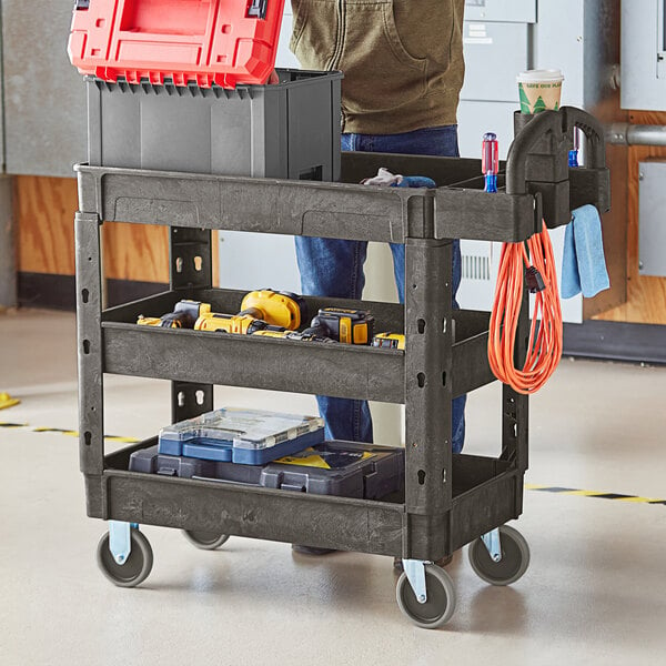 A man holding a Lavex black utility cart with tools on it.