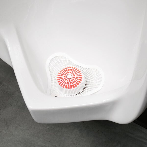 A white plastic urinal screen with a red circular center.