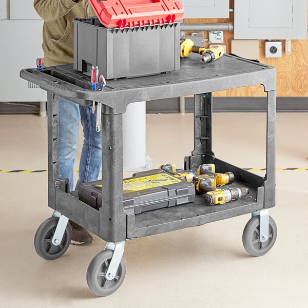 A man using a Lavex utility cart to hold tools, including a tool box.