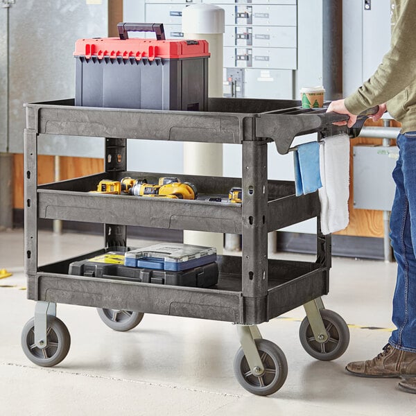 A man pushing a black Lavex utility cart full of tools.