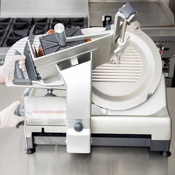 A person holding a Hobart meat slicer on a counter.