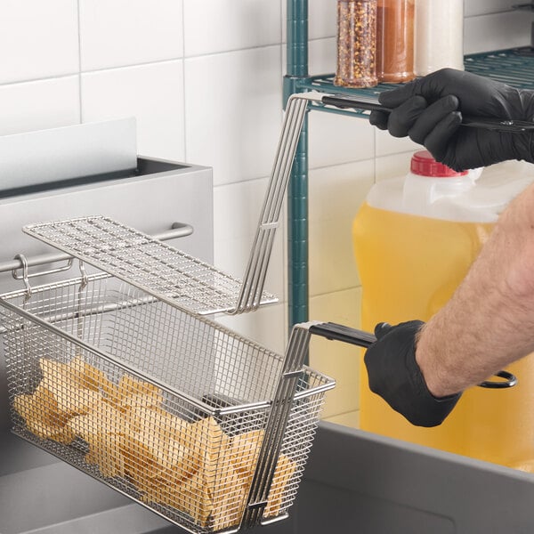 A 10 inch by 4 3/4 inch fryer basket press being used in a commercial kitchen.