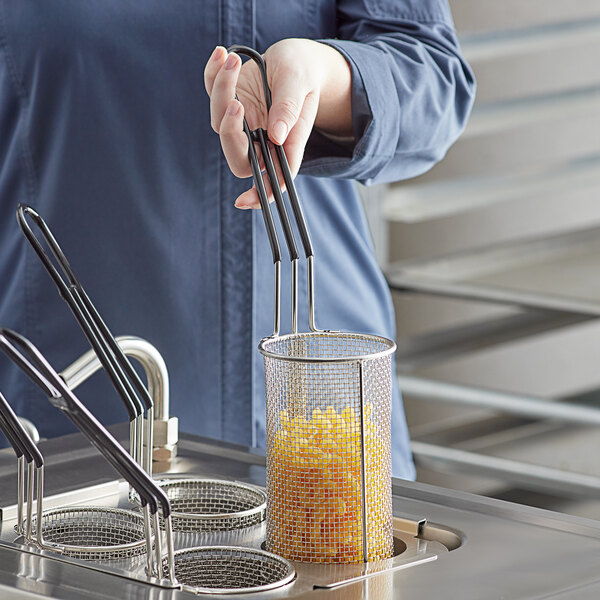 A person holding an Avantco pasta basket with food in it.