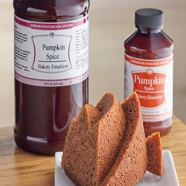 A slice of cake on a plate next to a bottle of LorAnn Oils Pumpkin Spice Bakery Emulsion.