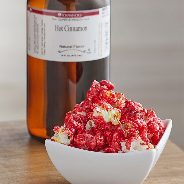 A bowl of popcorn next to a bottle of LorAnn Oils All-Natural Hot Cinnamon Super Strength Flavor.