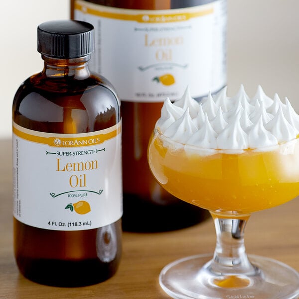 A glass of yellow liquid with whipped cream in it next to a bottle of LorAnn Oils Lemon Super Strength Flavor.