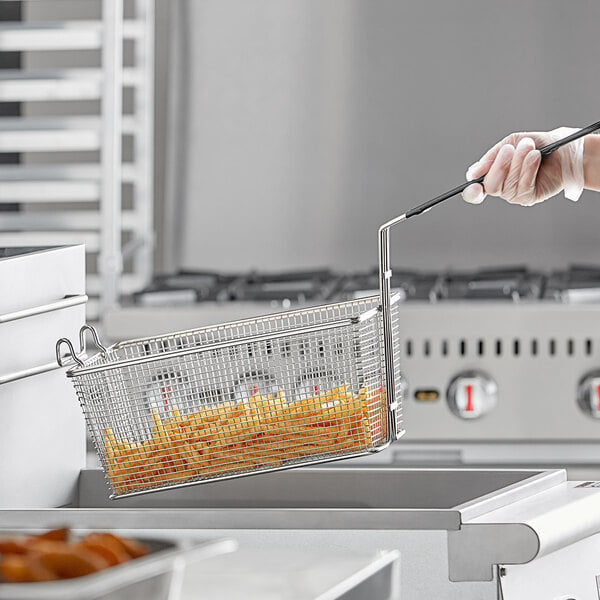 A hand holding an Anets twin fryer basket with food inside.